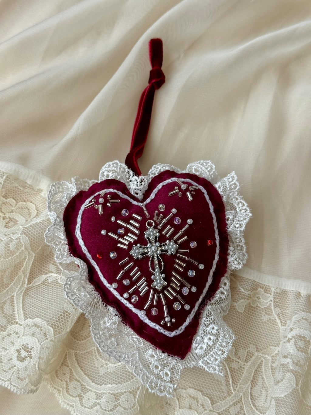 Decorative embroidered heart by Girdle of Venus with cross and lace on a textured fabric background
