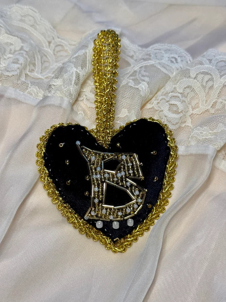 Heart-shaped brooch with gold and black design on a lace background