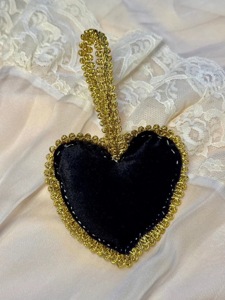 Black heart-shaped ornament with gold trim on a lace background