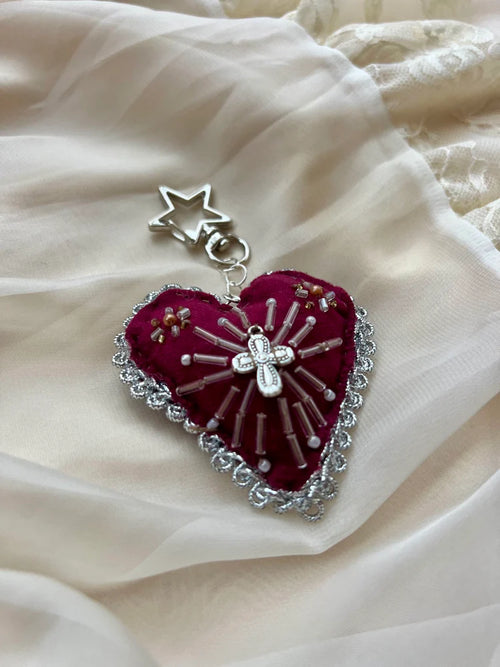 Heart-shaped pendant with star and cross on a soft fabric background