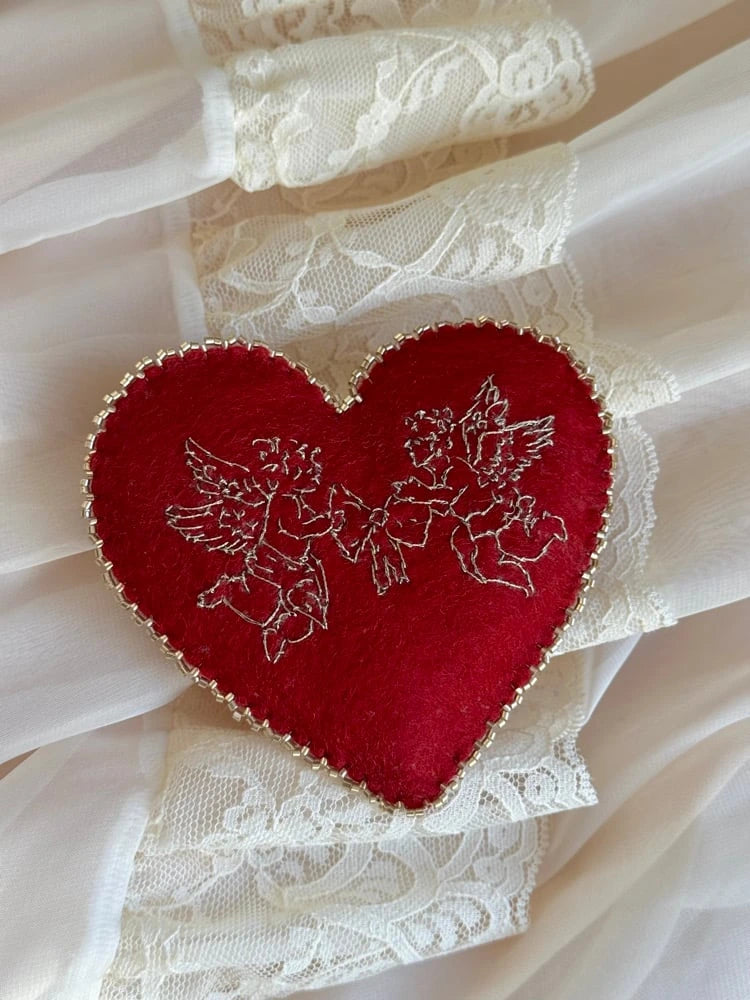Red heart-shaped cherub embroidered pillow on lace fabric