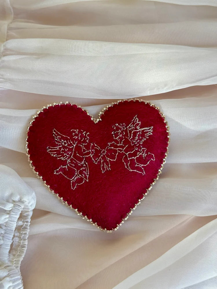 Red heart-shaped cherub embroidered pillow on lace fabric