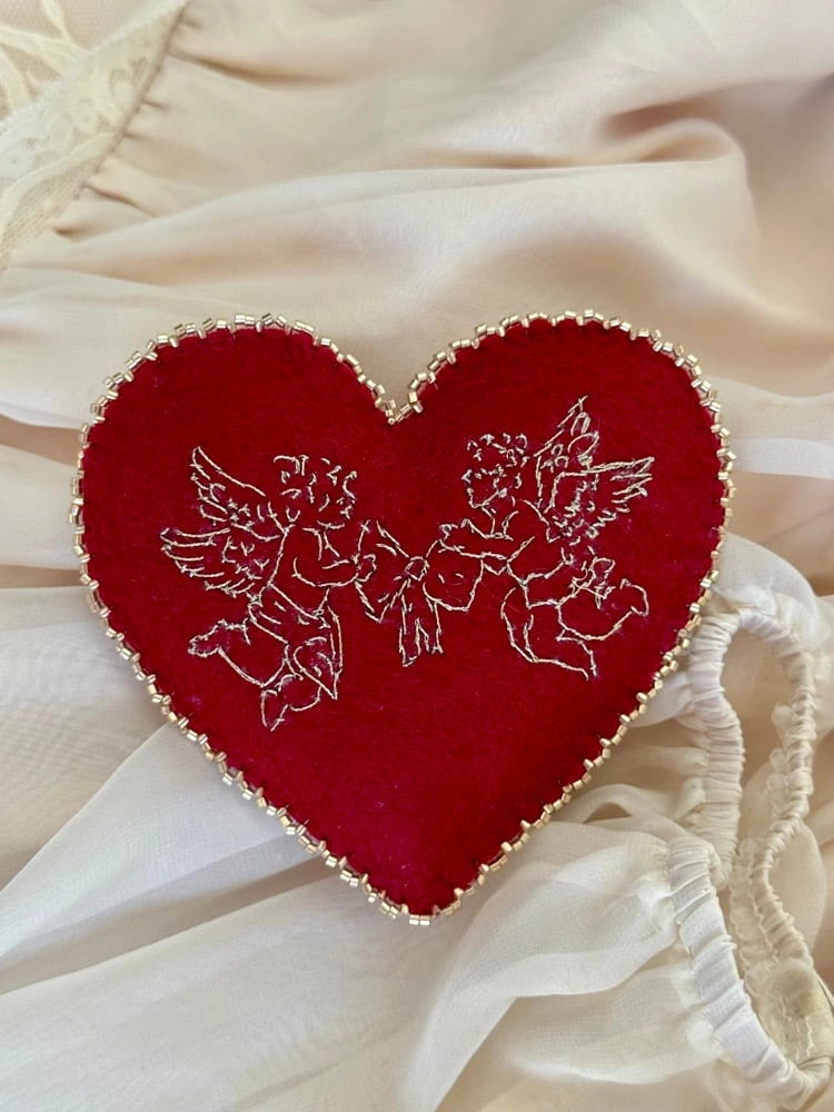 Red heart-shaped cherub embroidered pillow on lace fabric