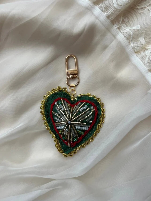 Heart-shaped keychain with intricate design on a white fabric background