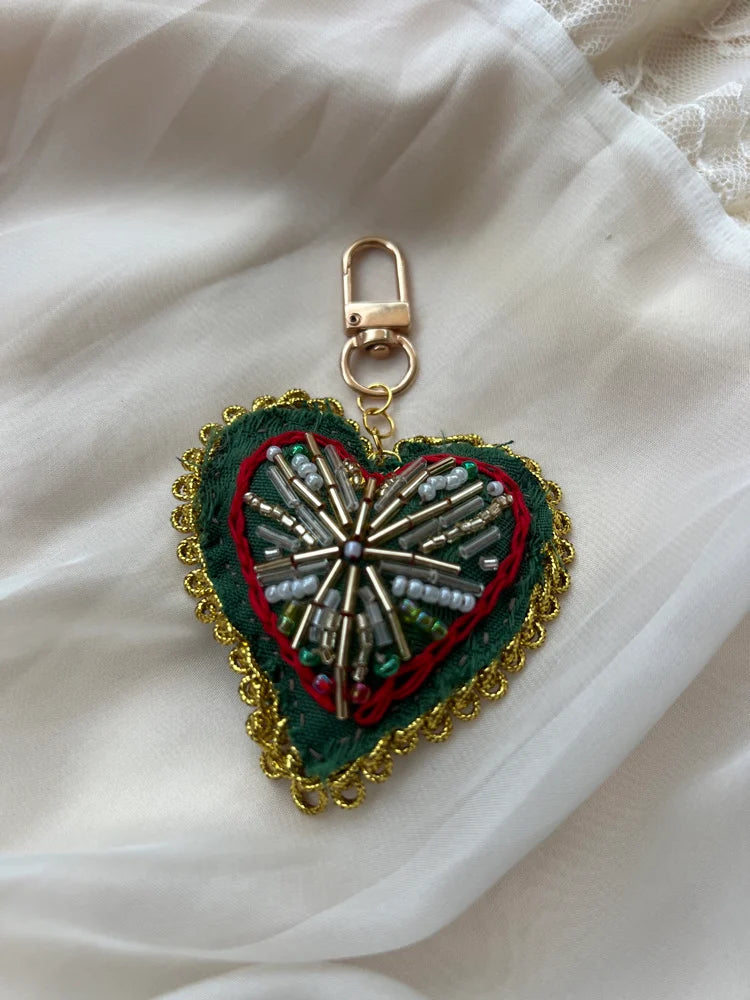 Heart-shaped keychain with decorative elements on a white fabric background