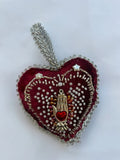 Heart-shaped pendant with hand and heart design on a white background