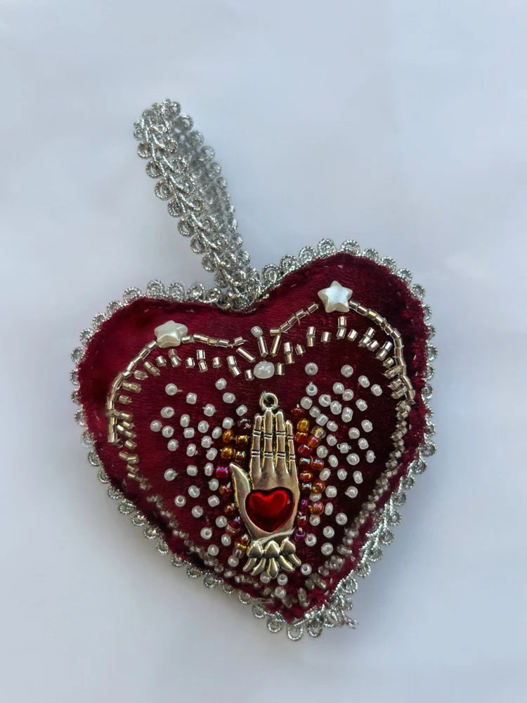 Heart-shaped pendant with hand and heart design on a white background