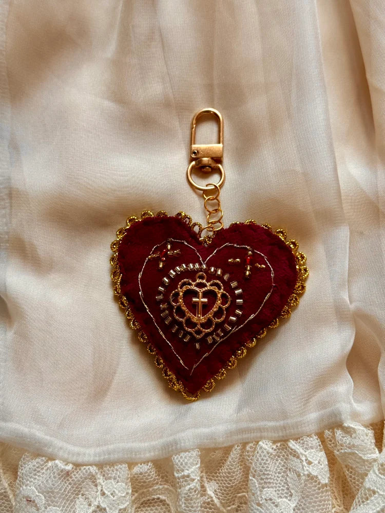 Heart-shaped embroidered keychain on a lace fabric background