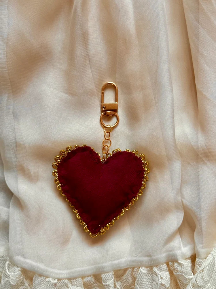 Heart-shaped keychain with gold trim on a white fabric background