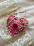 Pink heart-shaped embroidered ornament on a lace background