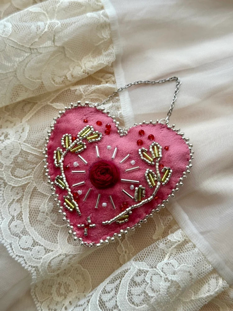Pink heart-shaped embroidered ornament on a lace background
