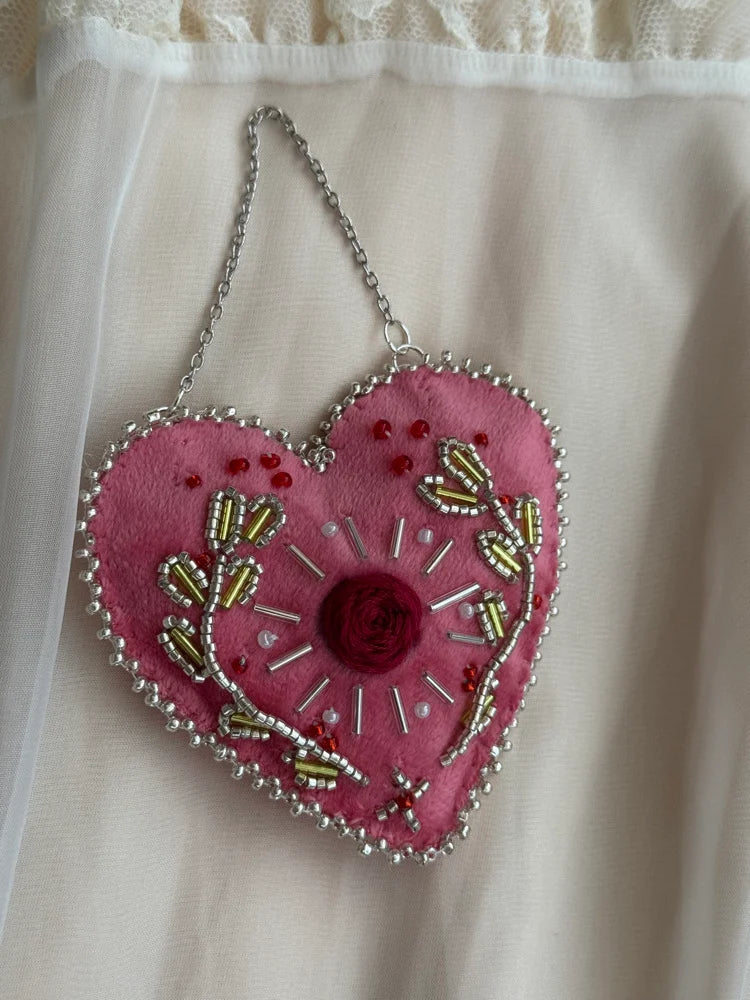 Pink heart-shaped embroidered bag with floral patterns on a sheer fabric background