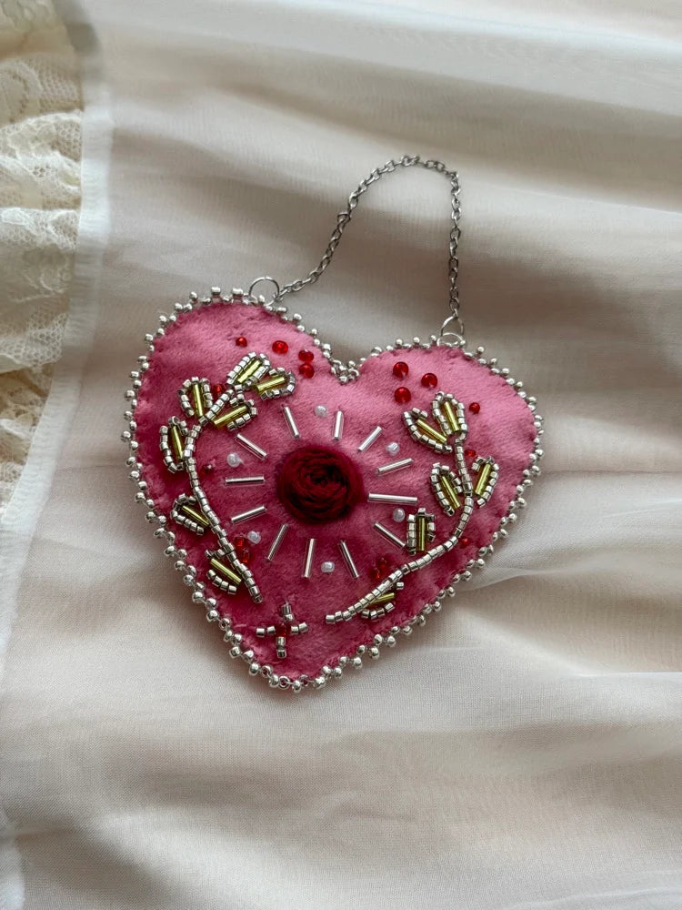 Heart-shaped embroidered pendant on a soft fabric background