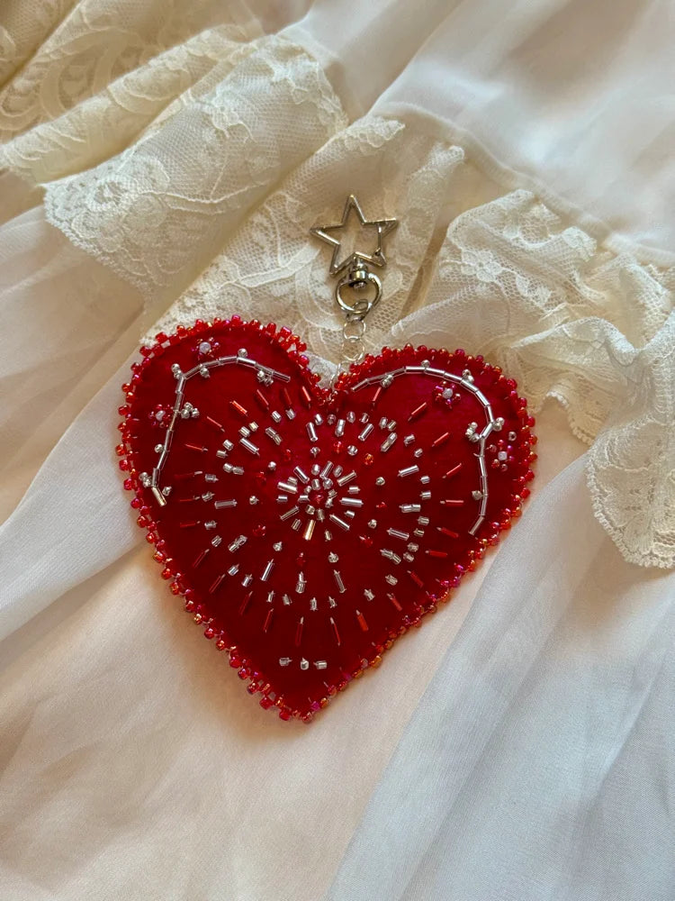 Red heart-shaped embroidered design on a white lace fabric background