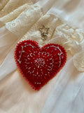 Red heart-shaped embroidered design on a white lace fabric background