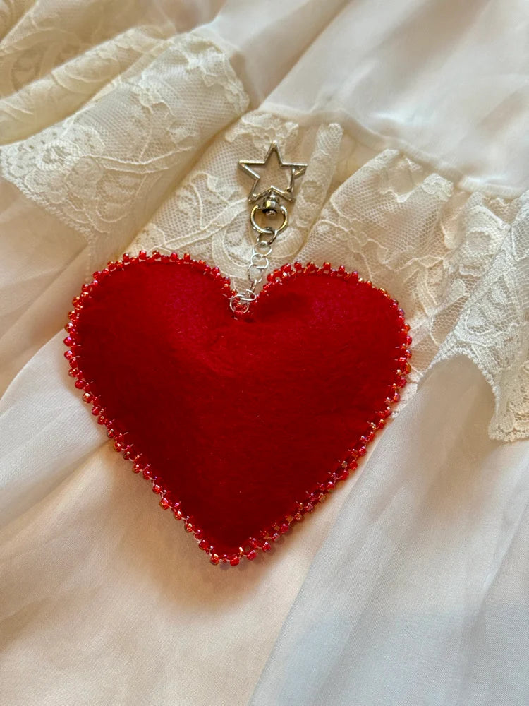 Red heart-shaped pendant with beads on a lace fabric background