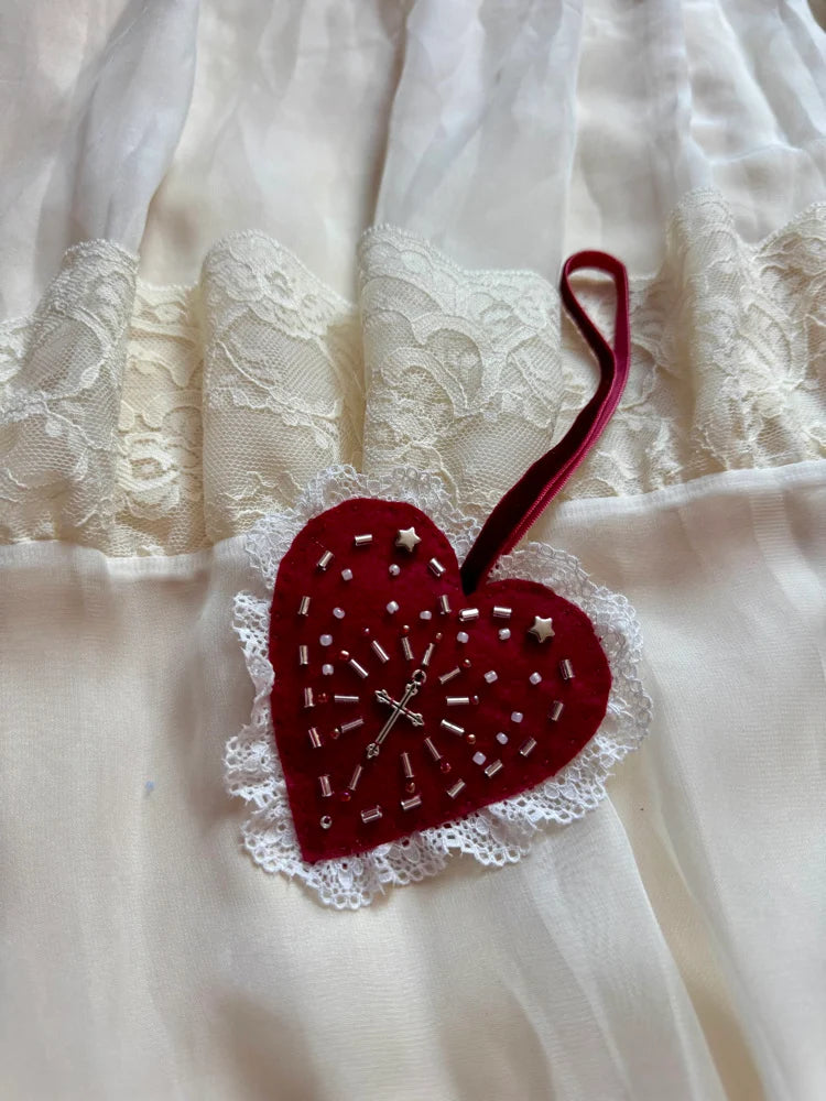 Red heart-shaped ornament with lace details on a white fabric background