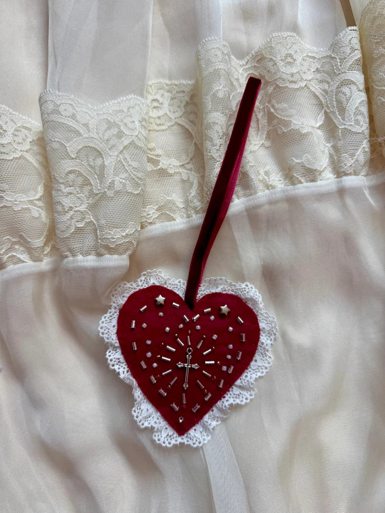 Red heart-shaped lace ornament on a white lace fabric background