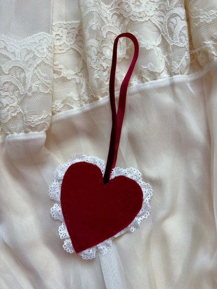 Red heart-shaped ornament with lace edge on a white lace fabric background