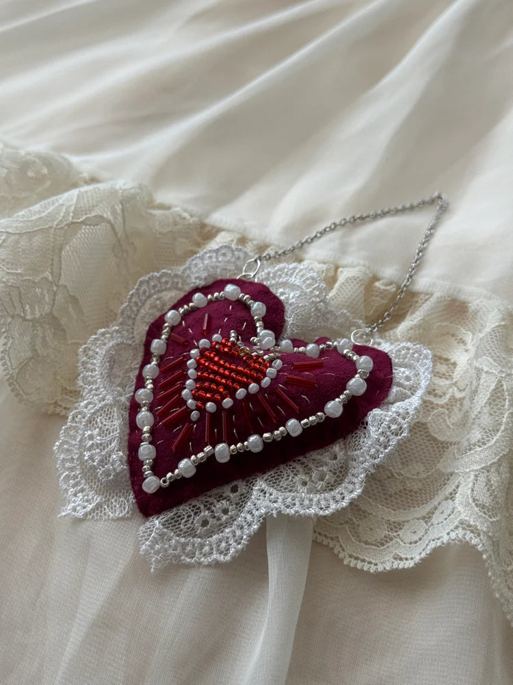 Heart-shaped decorative item with beads on a lace background