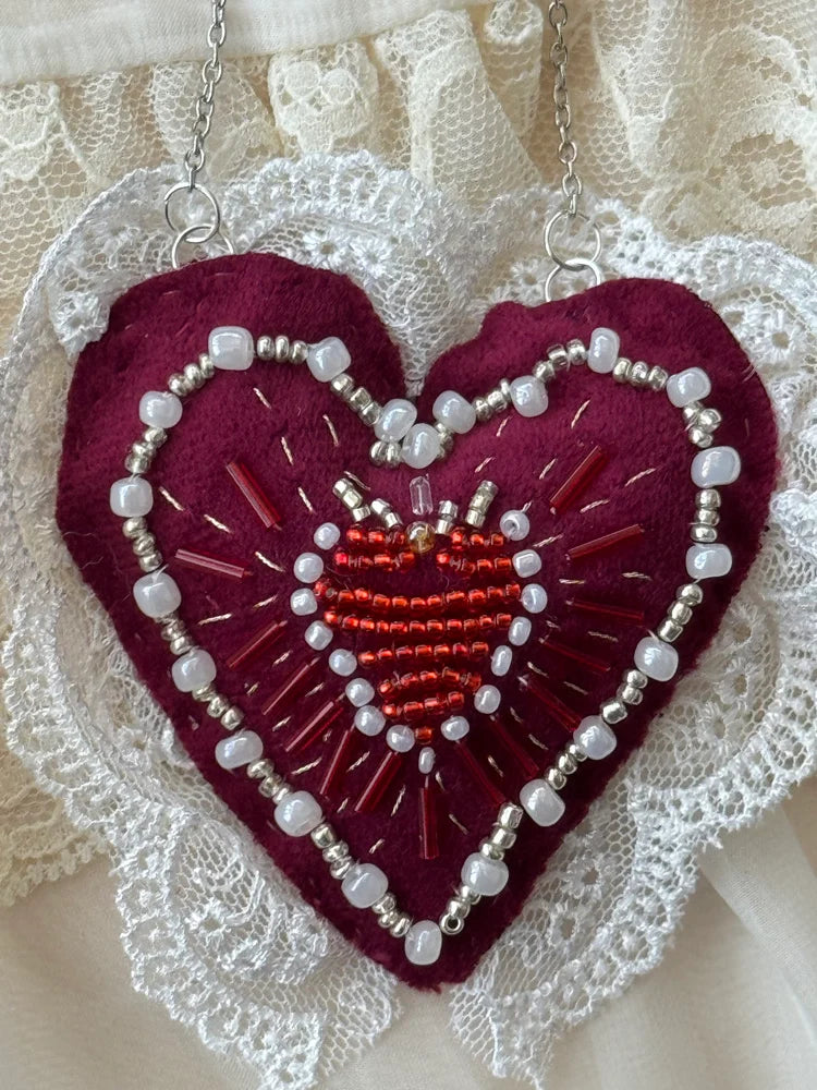 Embroidered heart pendant with beads on a lace background