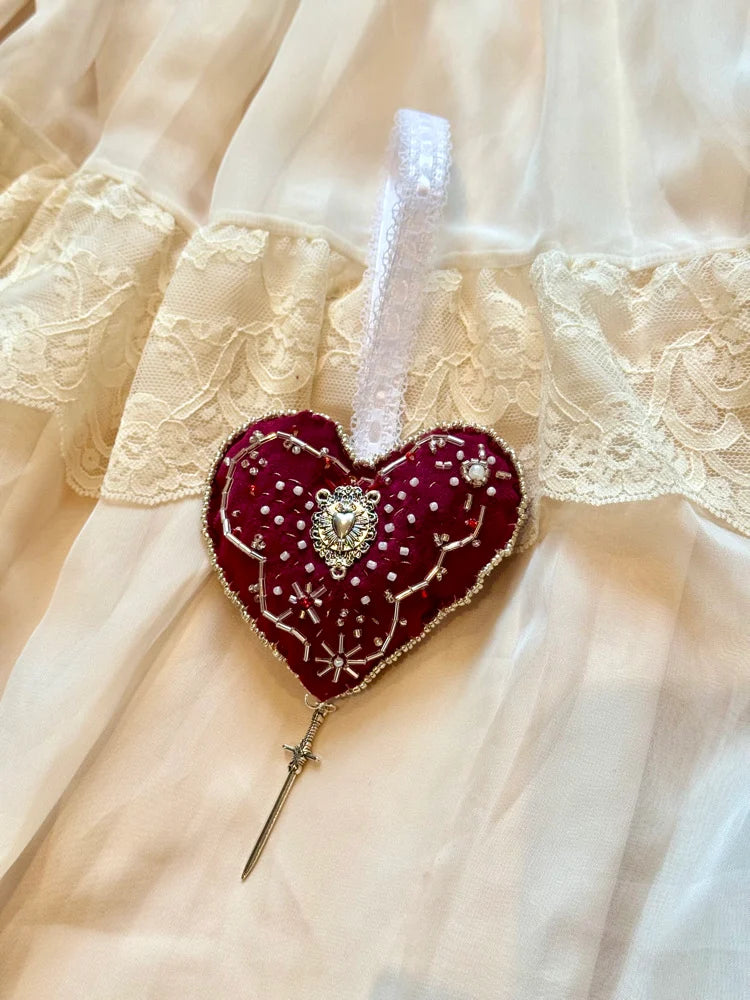 Decorative heart-shaped ornament with a sword on a lace background
