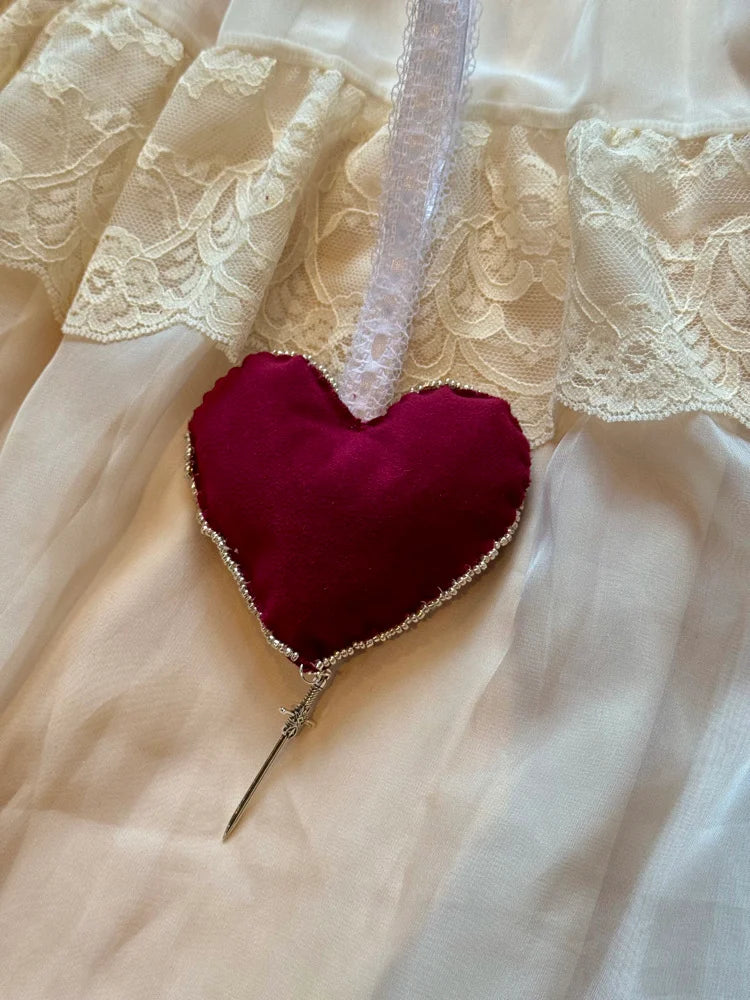 Red heart-shaped object with a decorative element on a lace fabric background