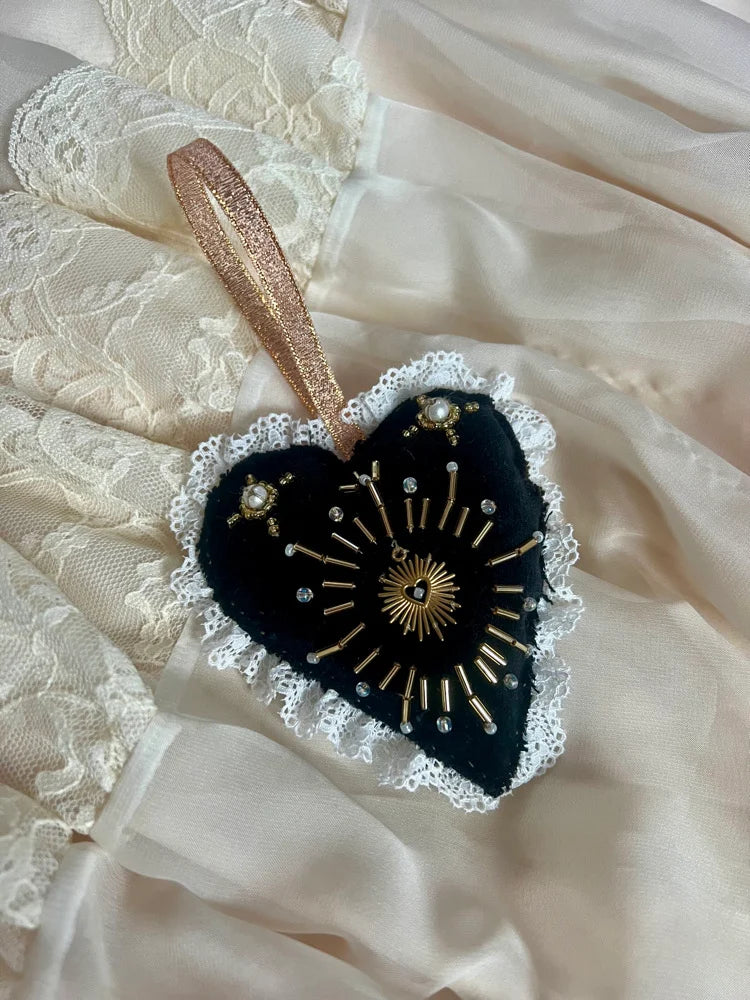 Decorative heart-shaped ornament with lace details on a textured fabric background
