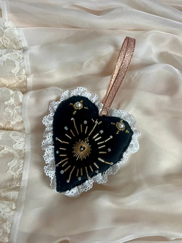 Decorative heart-shaped object with lace details on a soft fabric background