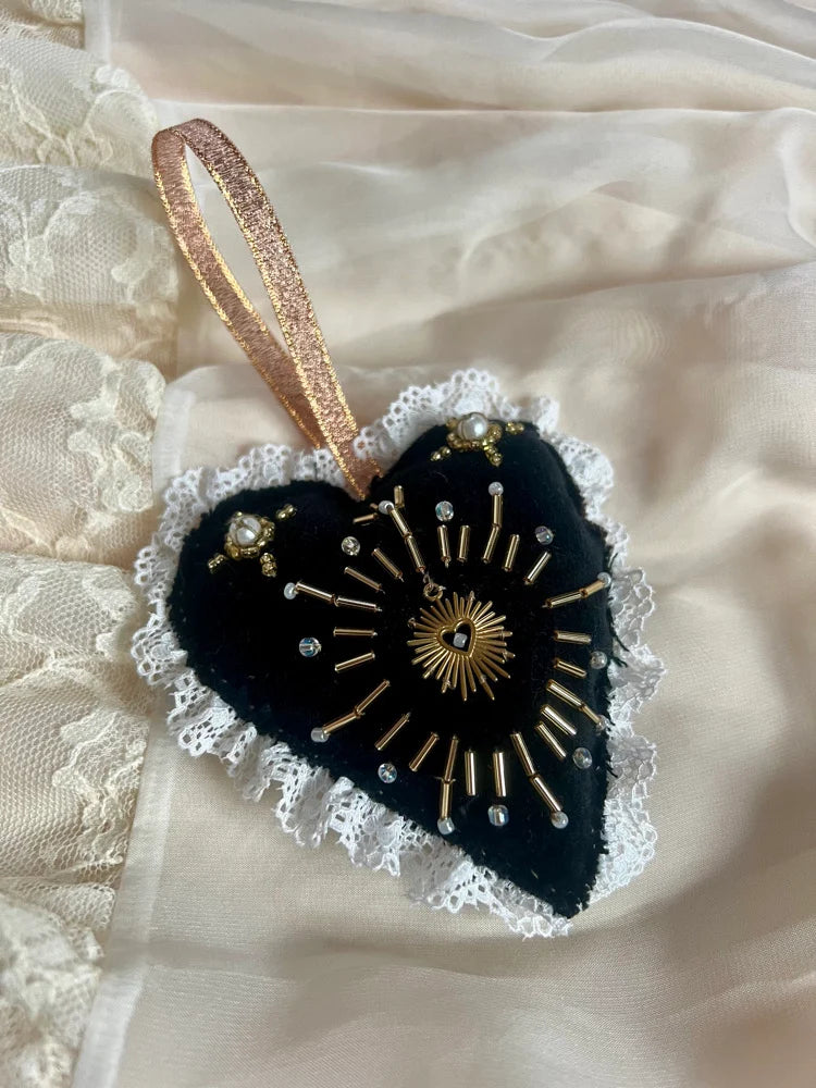Decorative heart-shaped ornament with gold details on a textured beige background