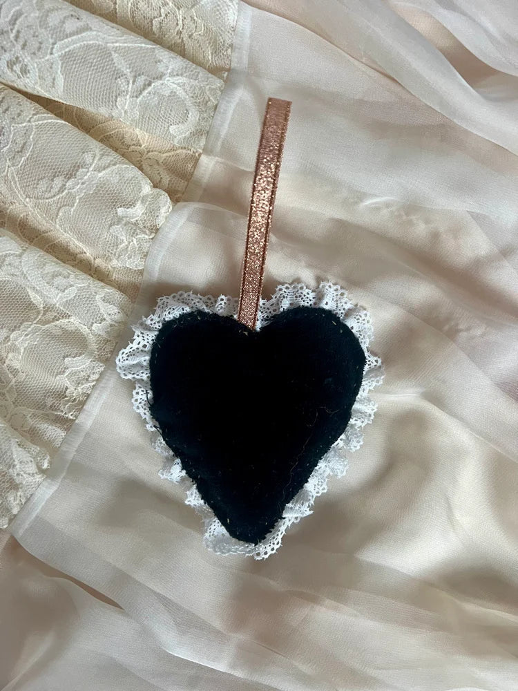 Black heart-shaped ornament with lace edge on a sheer fabric background