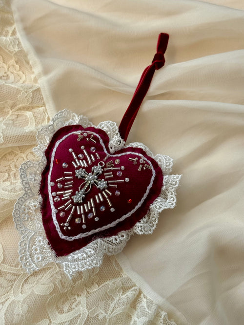 Heart-shaped embroidered decoration by Girdle of Venus on a lace fabric background