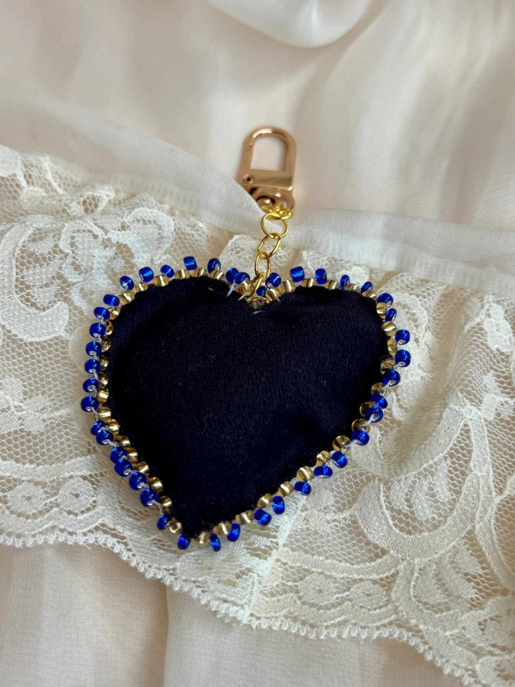 Heart-shaped keychain with blue beads on a lace background