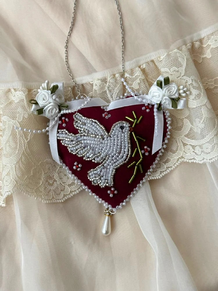 Heart-shaped pendant wall hanging with beaded dove design and satin roses on a lace background