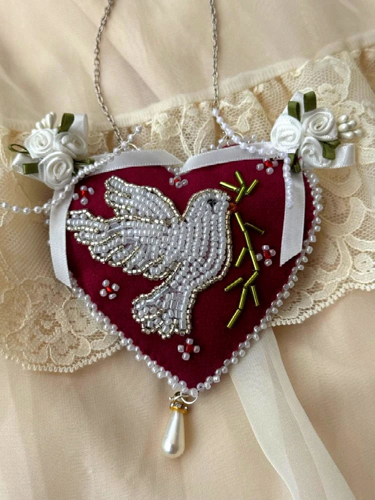 Heart-shaped pendant wall hanging with beaded dove design and satin roses on a lace background