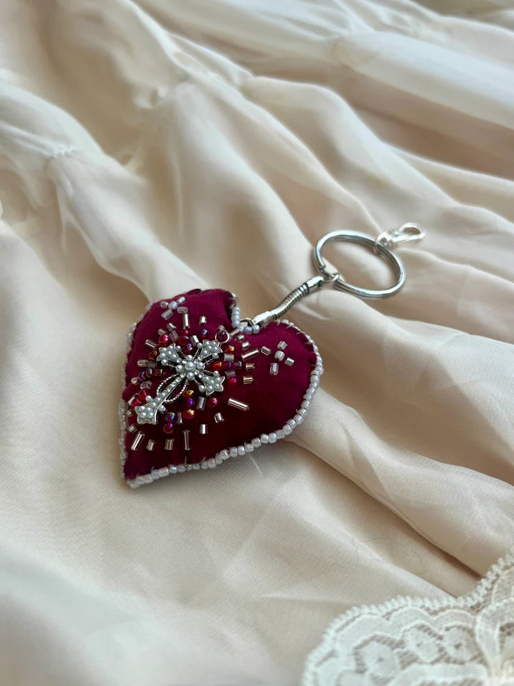 Heart-shaped keychain with beads on a soft fabric background
