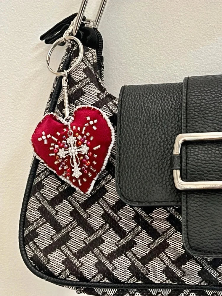 Black and gray patterned handbag with a red heart-shaped keychain featuring white designs.