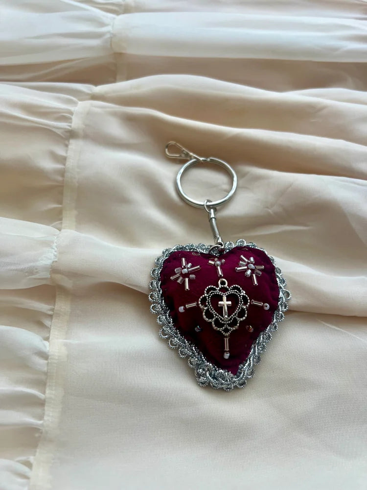 Heart-shaped keychain with intricate designs on a light fabric background