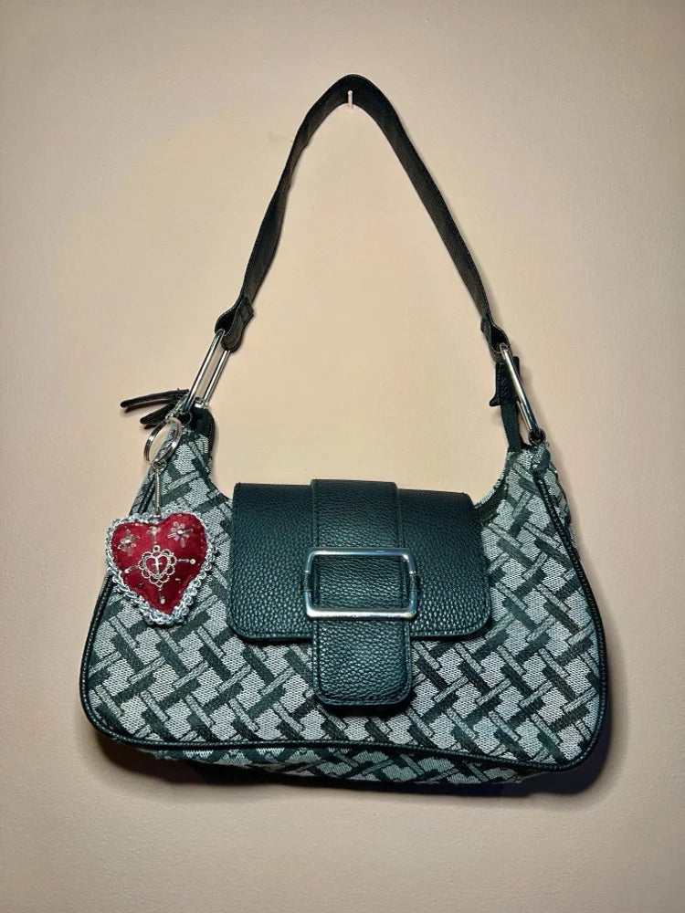 Grey patterned handbag with a red sacred heart design keychain on a beige background