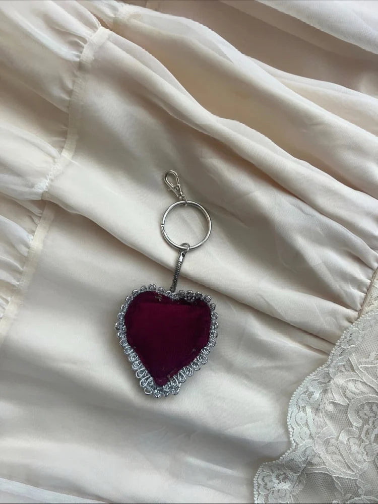 Heart-shaped keychain with red center and silver border on a white fabric background