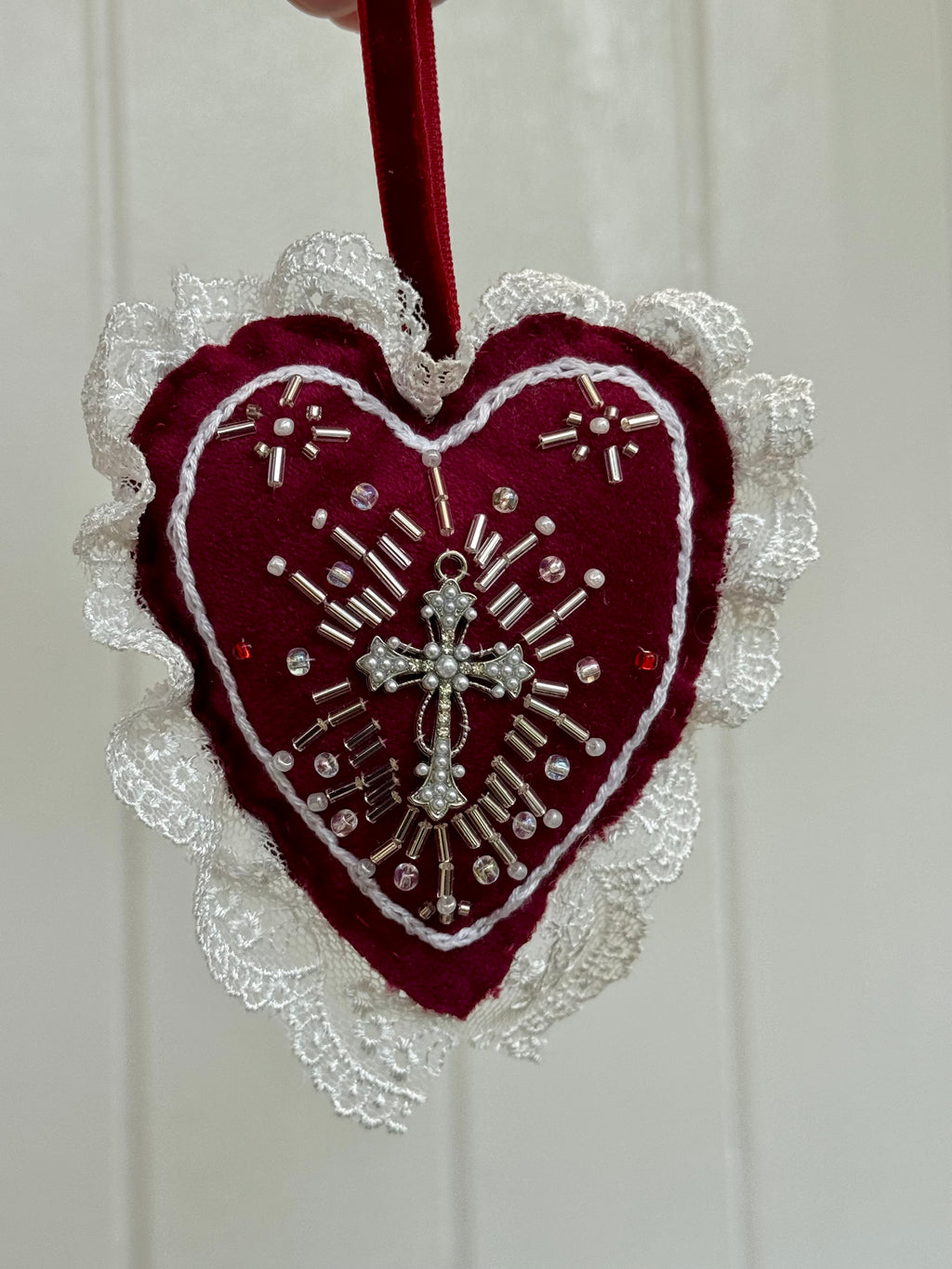 Decorative heart ornament with lace and cross design on a white background