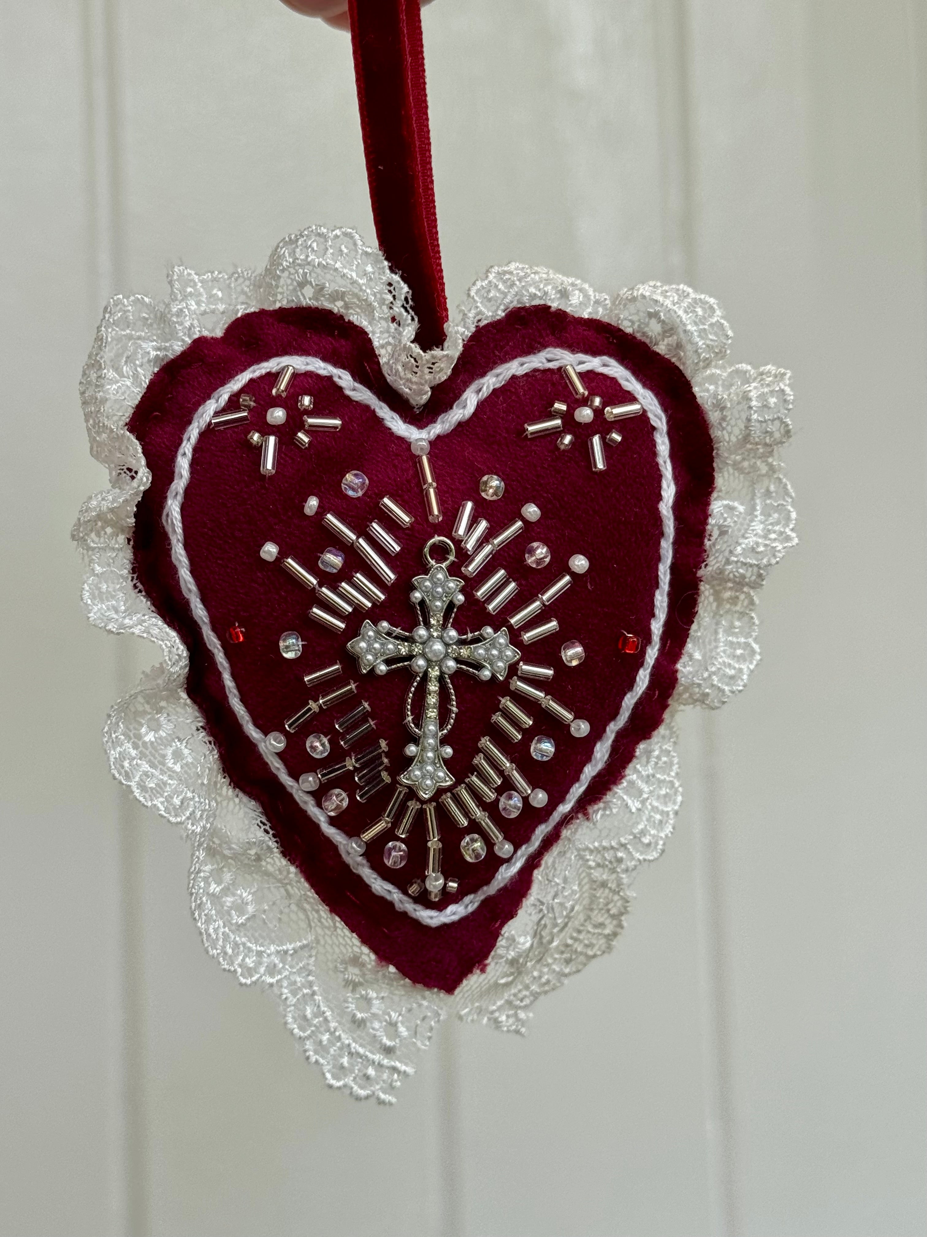 Decorative heart ornament with lace and cross design on a white background