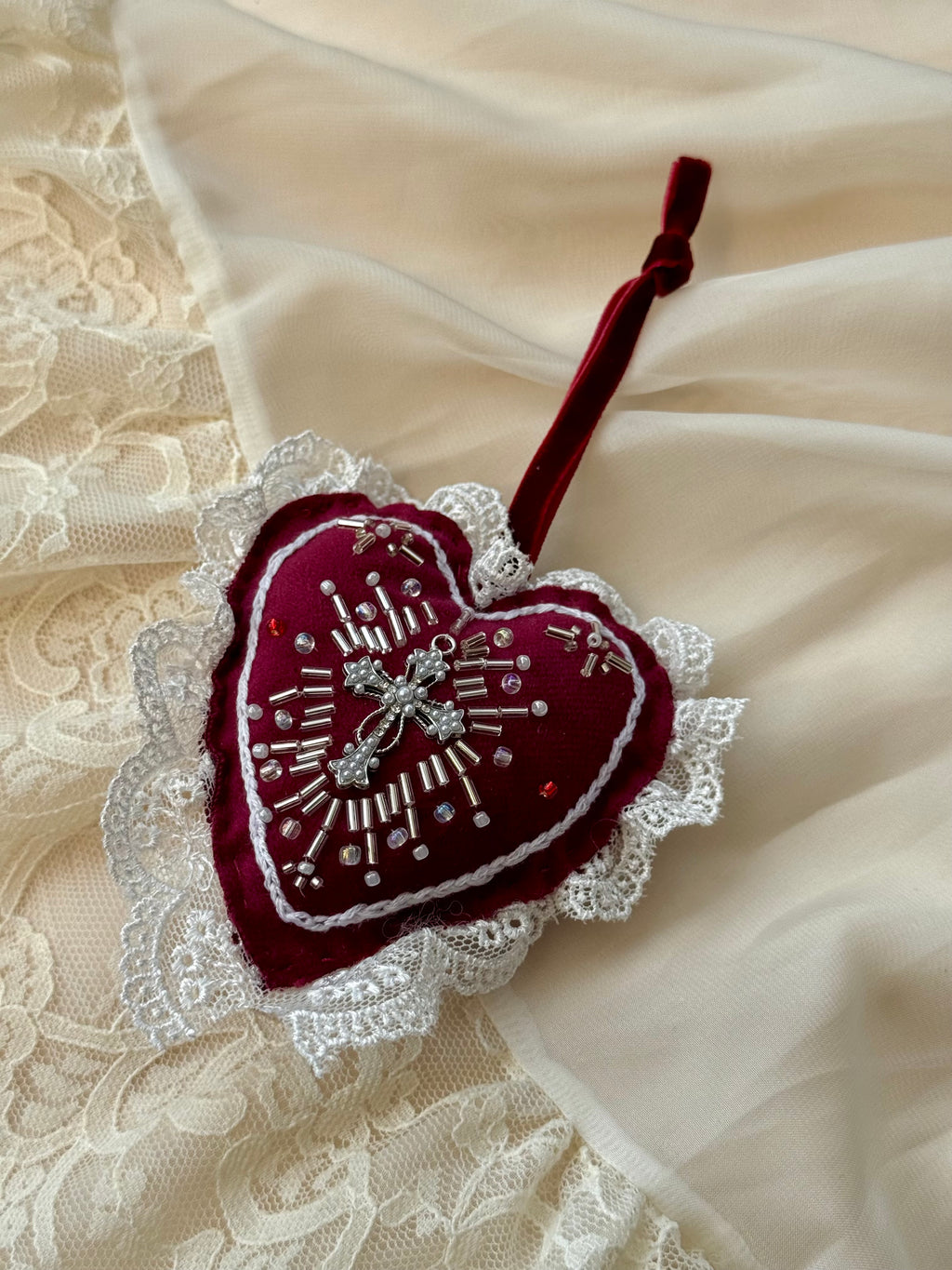 Decorative heart ornament by Girdle of Venus with lace details on a textured fabric background