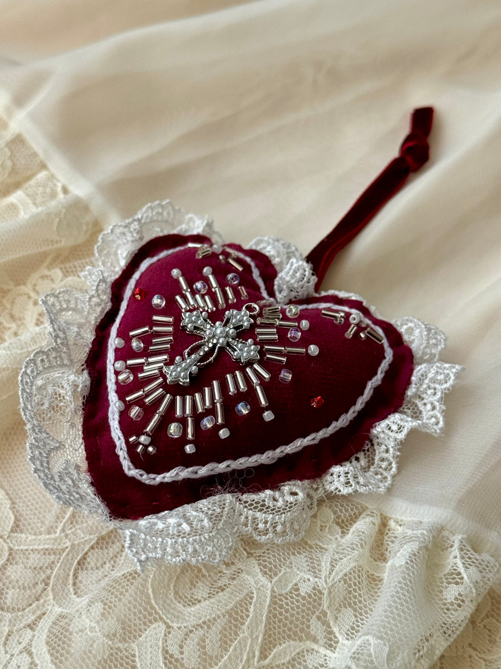 Heart-shaped embroidered piece by Girdle of Venus on a lace fabric background