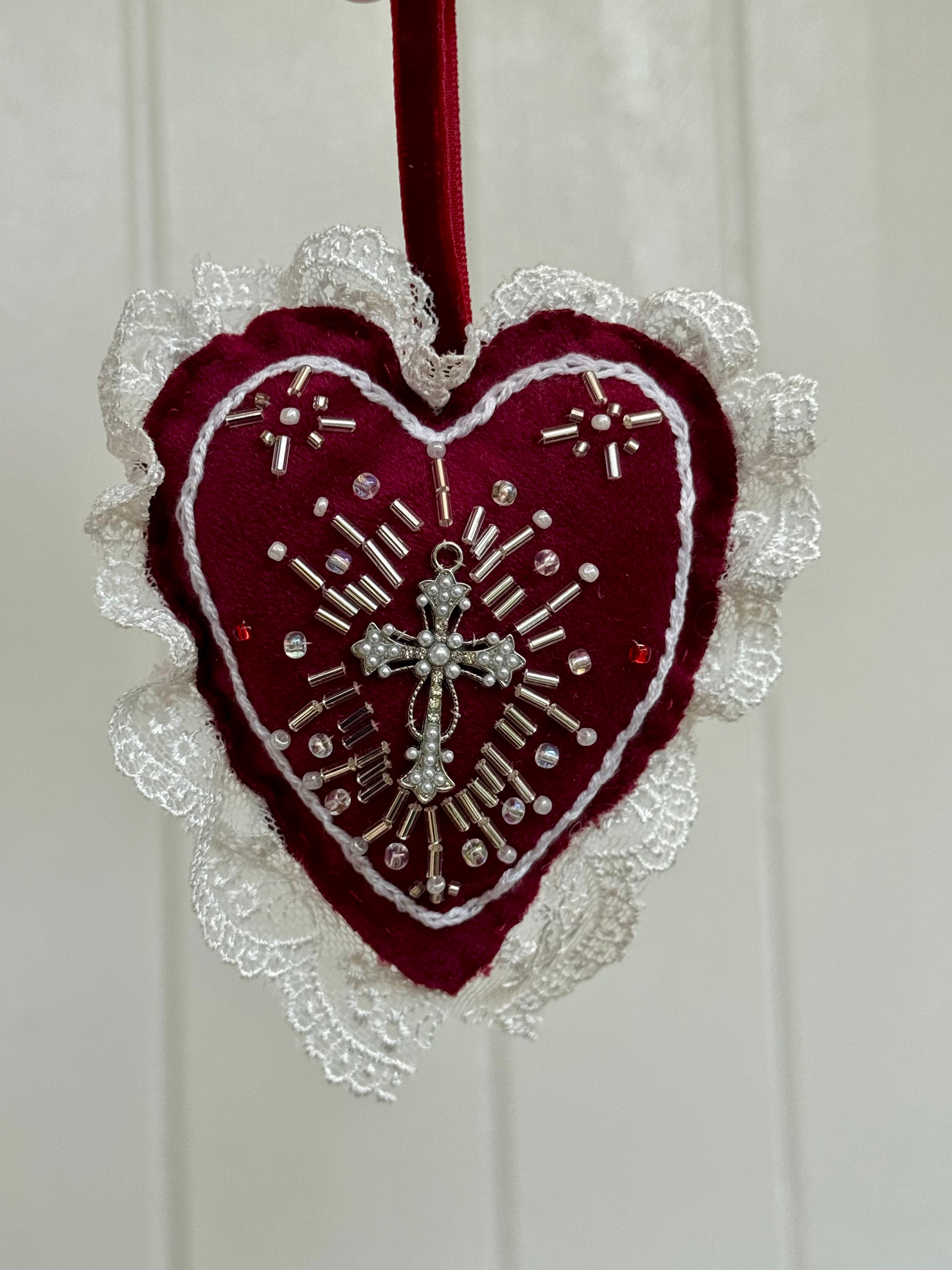 Heart-shaped decorative item by Girdle of Venus with lace and cross design on a white background