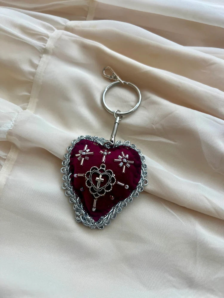 Heart-shaped keychain with intricate design on a light fabric background