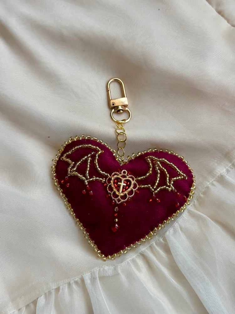 Heart-shaped keychain with bat designs on a white fabric background