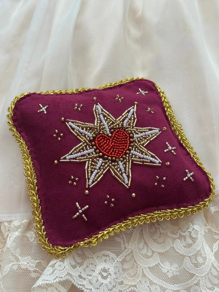Decorative pillow with embroidered heart design on a lace background