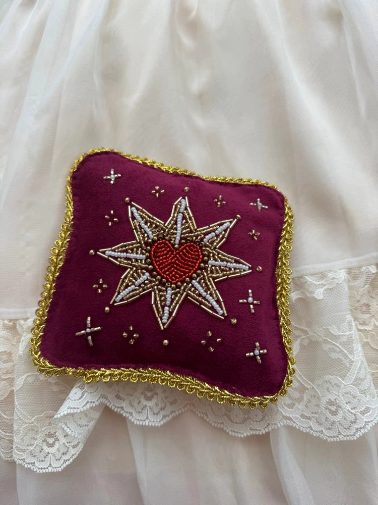 Decorative pillow with embroidered design on a white lace fabric background