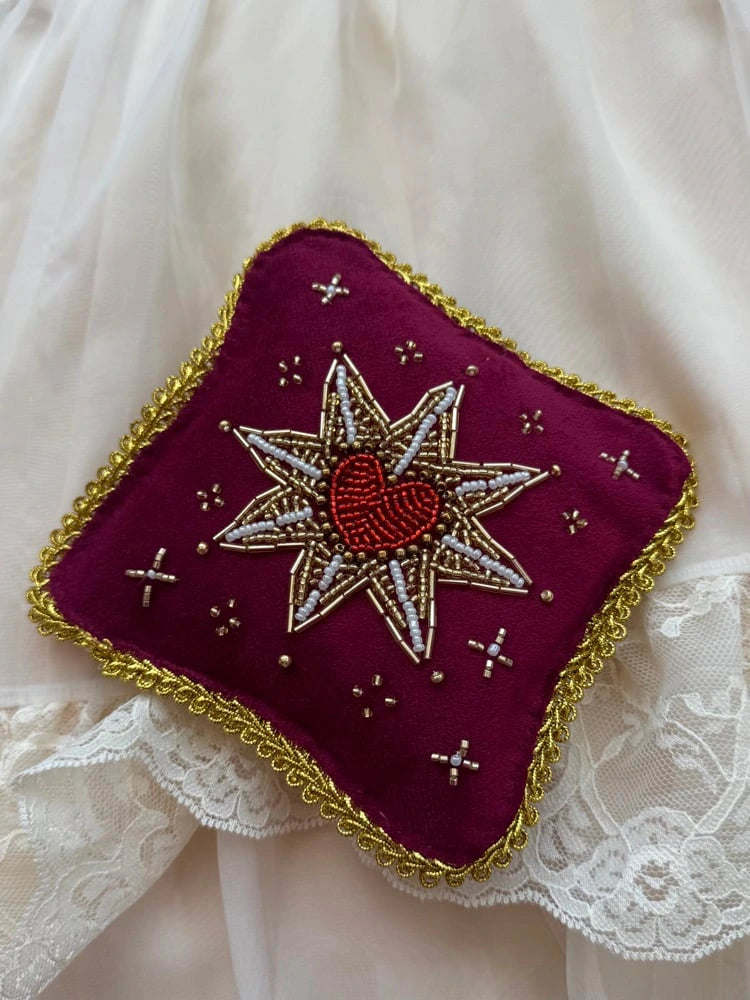 Decorative cushion with star and heart design on a white lace background